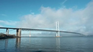 Deniz körfezi üzerindeki köprülerin üzerinde hareket eden bulutlar. Büyük bir köprünün hızlandırılmış videosu. Dördüncü Yol Köprüsü ve Queensferry Köprüsü, İskoçya, Birleşik Krallık