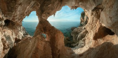 Sardunya 'nın Cala Gonone yakınlarındaki büyük bir mağaradan deniz taşlı kıyı şeridi manzarası. İtalya. Tatil tatili afişi, yaz tatili.