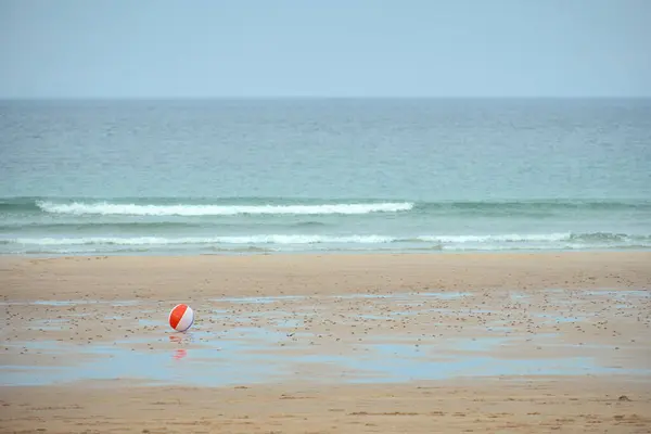 Childrens multi-coloured ball rolling in the wind on a sea beach. Scotland