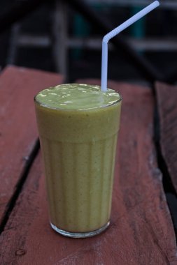 Taze avokado meyve suyu ve kafedeki ahşap masa.