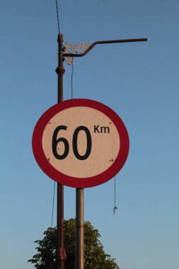 Sabah mavi gökyüzüne karşı hız sınırlandıran yol işareti.