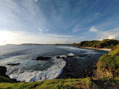 Mandalika, Lombok 'ta gün boyunca kayalık bir sahilde dalgalar ve plaj manzarası