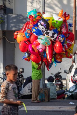 Bir balon satıcısı kalabalığın ortasında satıyor, Bertais Lombok, Endonezya, 23 Haziran 2024