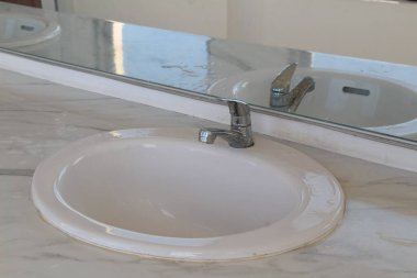 Mermer tezgahta beyaz seramik lavabosu olan banyo.