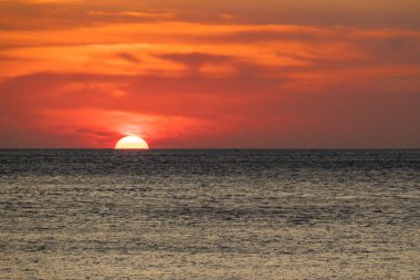 Ufuk çizgisinin üzerinde batan güneşli engin okyanus.
