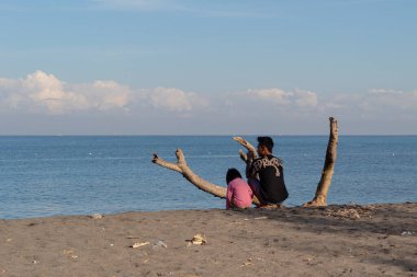 Baba ve oğul 14 Temmuz 2024 'te Lombok, Endonezya' da Loang Baloq plajında rahatlar ve dinlenirler.