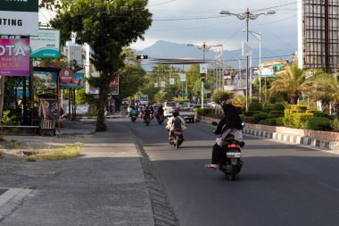 Mataram, Lombok, Endonezya 'da işlek bir şehir sokağındaki trafik ışıklarında motosikletli ve arabalı insanlar bekliyor - 24 Ağustos 2024