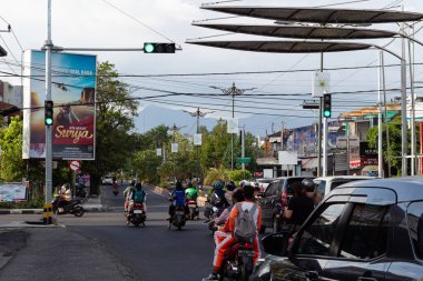 Mataram, Lombok, Endonezya 'da işlek bir şehir sokağındaki trafik ışıklarında motosikletli ve arabalı insanlar bekliyor - 24 Ağustos 2024