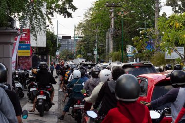 Mataram, Lombok, Endonezya 'da işlek bir şehir sokağındaki trafik ışıklarında motosikletli ve arabalı insanlar bekliyor - 24 Ağustos 2024