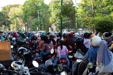 24 Ağustos 2024 'te Mataram, Lombok, Endonezya' da bir halk etkinliği sırasında büyük bir insan ve motosiklet kalabalığı ağaç sıralı bir caddeyi kuşatıyor.