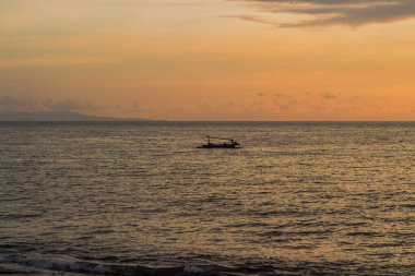 Uçsuz bucaksız okyanusun üzerinde altın bir günbatımına karşı küçük bir balıkçı teknesi.