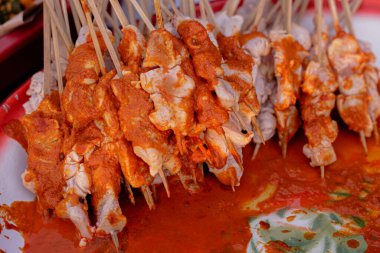 Canlı kırmızı salamura ile kaplanmış çiğ tavuk şişleri ızgara için hazır.