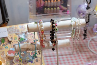 Kırsal bir ahşap stantta sergilenen renkli el yapımı boncuklu bilezik koleksiyonu. Mataram, Endonezya 'da 10 Kasım 2024