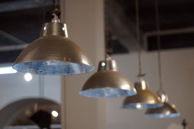 Metalik endüstriyel kolye ışıkları içeride tavandan sarkıyor.