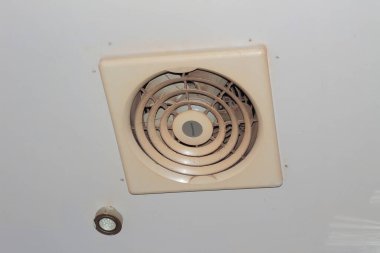 Kirli kare plastik egzoz vantilatörü beyaz tavana monte edilmiş.