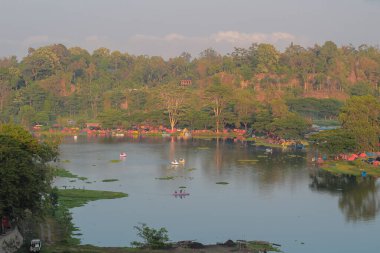 Kamp alanı, orman tepeleri ve eğlence amaçlı pedal tekneleri olan manzaralı göl manzarası.