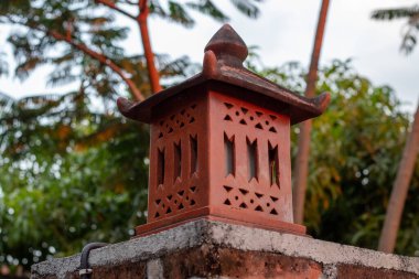 Dışarıdaki taş ve tuğla duvarların üzerindeki geleneksel terakotta kil feneri manzarasını kapat.