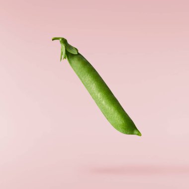 Pembe zemine izole edilmiş taze taze taze taze taze bezelye kabukları düşüyor. Gıda havalanması veya sıfır yerçekimi kavramı