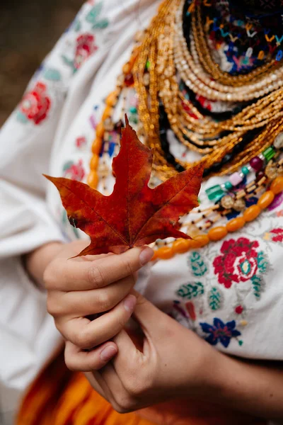 Geleneksel Ukrayna elbiseli kadın elinde sonbahar akçaağaç yaprağı
