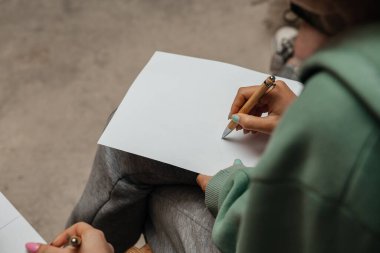 Genç bir kadın beyaz bir kağıda kalemle yazıyor.