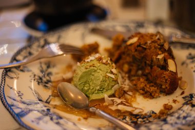 Lokantada lezzetli bir tatlı: Bir kepçe çikolatalı ve balkabaklı kek serpiştirilmiş ay çekirdeği tohumlu tatlı sos serpiştirilmiş güzel bir tabak desenli