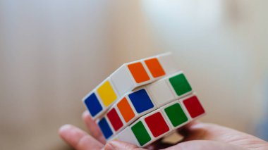 Kadın elleri bir rubik küp tutuyor.