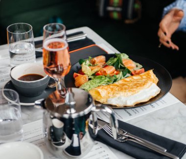 Restoran masasında yeşil marul yapraklı ve somon dilimli omlet.