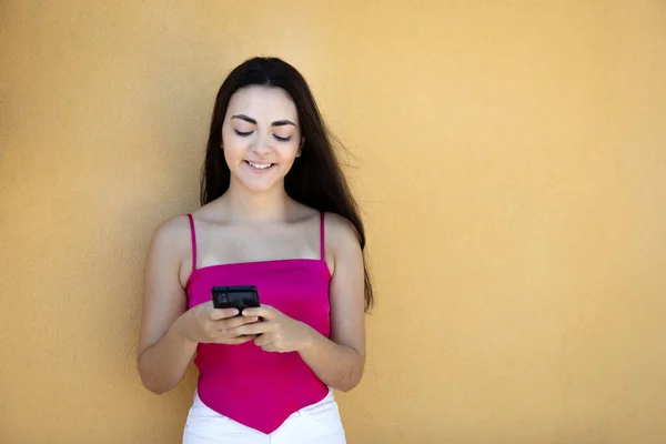 Портрет Красивої Темноволосої Дівчини Підлітка Рожевому Верхньому Одязі Дивлячись Мобільний — стокове фото