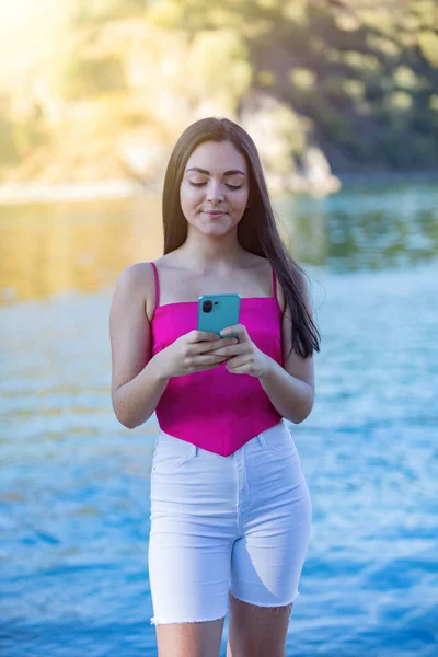 有智能手机的欧洲青少年 模糊的背景 长发配粉红衬衫 — 图库照片
