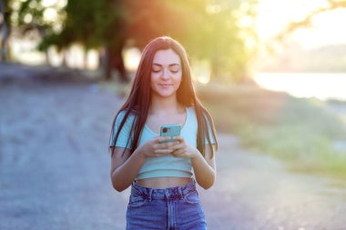 Kırsalda güzel esmer kız akıllı telefon kullanıyor. 