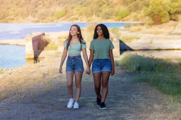 晴れた日に川の近くを歩く田舎の2人の女の子の友人 — ストック写真