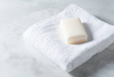 Beyaz havlu ve katı sabun mermer zemine yerleştirilmiş.. 