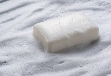 Köpükten bir arka plana yerleştirilmiş beyaz katı sabun. 