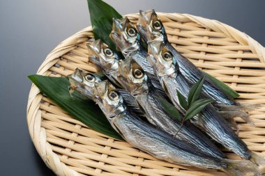 Ulmae sardines served in a colander placed on a black background. Japanese food, dried fish.