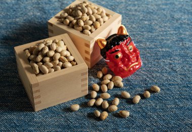 Beans for bean-throwing and masks of ogres placed on a navy blue background. Japanese ogres. Setsubun image. clipart