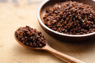 Sichuan biberi ve tahta kaşık masada. Sichuan biberi Çin mutfağında kullanılan Sansho ailesinin bir üyesidir.. 