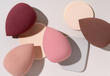 Bej arka planda birden fazla yumurta şekilli makyaj süngeri var. Yukarıdan görüntüle.