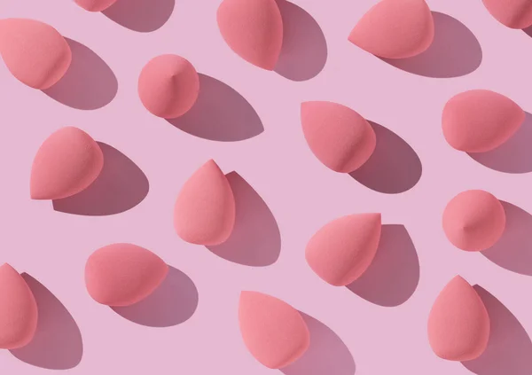 ピンクの背景に複数の卵型の化粧スポンジを配置しました 上からの眺め — ストック写真