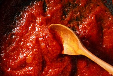 Tavadaki domates sosunu kaşıkla kepçele. Yemek pişirme sahnesi. Yukarıdan görüntüle.