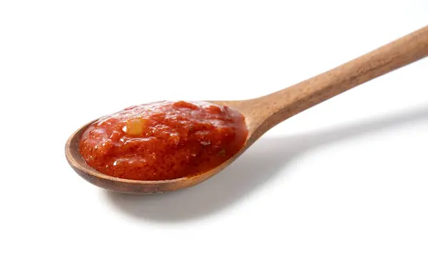 番茄酱在白色背景的木制勺子里 图库图片