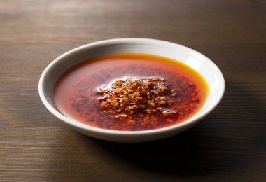 Ahşap arka planda seramik bir tabakta yenilebilir bir biber yağı..