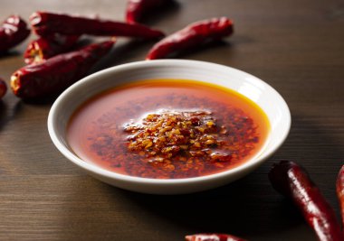 Ahşap arka planda seramik bir tabakta yenilebilir bir biber yağı..