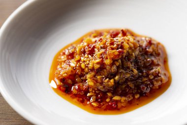 Ahşap arka planda seramik bir tabakta yenilebilir bir biber yağı..