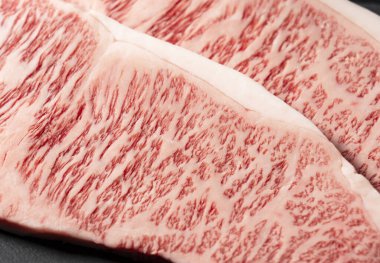 Siyah bir arka planda taştan bir tabağa taze çiğ biftek konmuş. Wagyu bifteği..