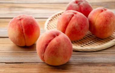 Japon şeftalileri ahşap bir arka planda kevgire servis edilir. Japon şeftalilerinin resmi.