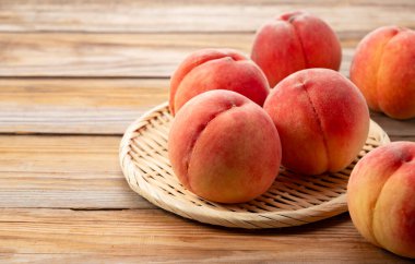 Japon şeftalileri ahşap bir arka planda kevgire servis edilir. Japon şeftalilerinin resmi.