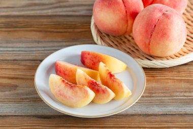 Ahşap bir zeminde servis edilen Japon şeftalilerini kes. Japon şeftalilerinin resmi.