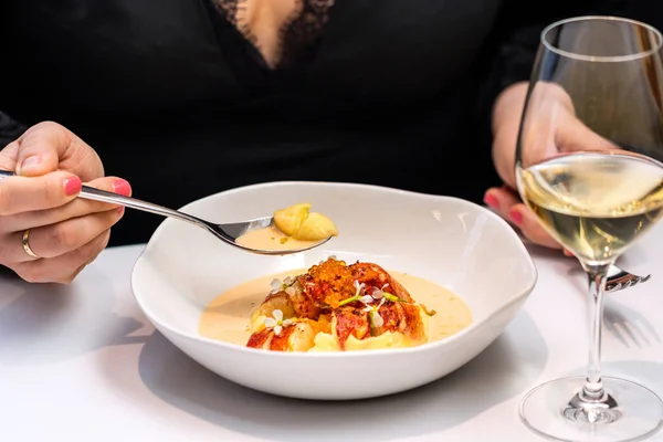 グルメレストランで夕食をとる女性の詳細を閉じます 白ワインのグラスの横にロブスタースープとスプーンを保持する女性の手 — ストック写真
