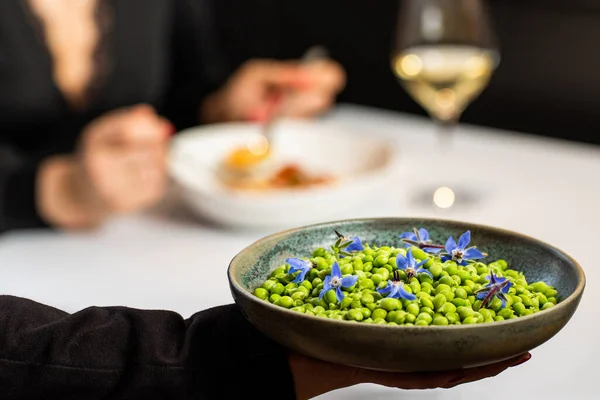Närbild Servitris Visar Färska Ärtor Med Kvinna Vid Middagsbordet Restaurang — Stockfoto