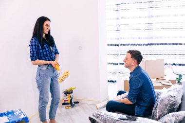 Genç, pozitif bir çift bir apartman dairesinde duvarları boyarken oynaşıyor. Bir adam kanepeye oturur ve elinde boya silindiri olan bir kız